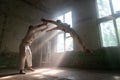 Male duo making acrobatic tricks wearing costume of insane people in abandoned room with sun rays from windows Royalty Free Stock Photo