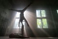 Male duo making acrobatic tricks wearing costume of insane people in abandoned room with sun rays from windows Royalty Free Stock Photo
