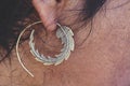 Male ear wearing brass earring in shape of leaf Royalty Free Stock Photo