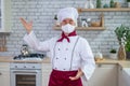 Male elderly chef in a medical mask in a restaurant kitchen Royalty Free Stock Photo