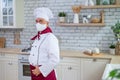 Male elderly chef in a medical mask in a restaurant kitchen Royalty Free Stock Photo