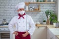 Male elderly chef in a medical mask in a restaurant kitchen Royalty Free Stock Photo