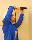 Male with electric drill making hole in wall