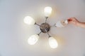 A male electrician changes the light bulbs in the ceiling light.