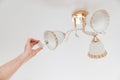 A male electrician changes the light bulbs in the ceiling light.