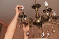 A male electrician changes the light bulbs in the ceiling light.