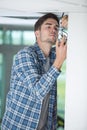 Male electrician fixing light on ceiling with screwdriver Royalty Free Stock Photo