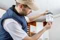 A male electrician fixing light on the ceiling.