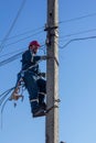 A male electrician rises up a reinforced concrete pillar for mounting electrical wires Royalty Free Stock Photo