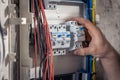 A male electrician works in a switchboard with an electrical connecting cable. Royalty Free Stock Photo