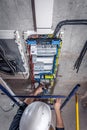 A male electrician works in a switchboard with an electrical connecting cable. Royalty Free Stock Photo