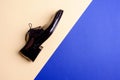 Male elegant black patent leather shoe on blue background with free space for ad.