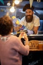 Male employee in fast food service smiling and talking to a customer while adding mustard in sandwich Royalty Free Stock Photo