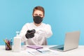 Male employee in hygienic mask and gloves rubbing hands, using antiseptic gel, disinfection to prevent coronavirus Royalty Free Stock Photo