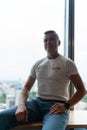 Male employee sits with contented expression on windowsill