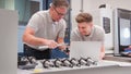 Male Engineer And Apprentice Measuring Components Whilst Looking At Laptop Royalty Free Stock Photo