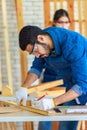 Male engineer architect foreman labor worker wears safety goggles using measuring tape measure wood plank on