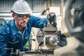 Male engineer in blue jumpsuit and white hard hat operating lathe machine. Royalty Free Stock Photo