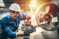 Male engineer in blue jumpsuit and white hard hat operating lathe machine. Royalty Free Stock Photo