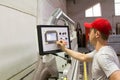 A male engineer controls the work of the machine in the furniture shop