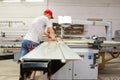 A male engineer controls the work of the machine in the furniture shop