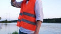 Male engineer holding helmet, posing outdoors with beautiful river on the background. Cropped, close up. High voltage Royalty Free Stock Photo