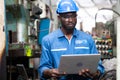 Male Engineer Working on laptop computer in Factory. black male engineer checking Quality control the condition of the machine.