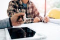 Male engineering using digital tablet with architectural plan on desk