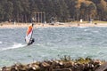 Male enjoying Windsurfing sail in Varamon sea waves near the sandy beach with trees coast