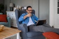 Male entrepreneur drinking coffee and making business plans over wireless computer while relaxing on armchair. Young handsome Royalty Free Stock Photo