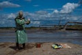 A male environmentalist in a green protective suit and gas mask takes a sample of water in a polluted lake for research