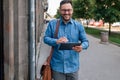 Male executive commuter is looking at hand held digital tablet screen while walking on sidewalk Royalty Free Stock Photo