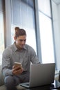 Male executive holding mobile phone while using laptop Royalty Free Stock Photo