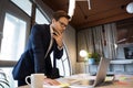 Male executive standing by table studying data on laptop screen