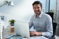 Male executive using laptop while looking at camera Royalty Free Stock Photo