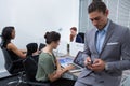 Male executive using mobile phone while colleagues working in background Royalty Free Stock Photo