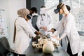 Male experienced mature doctor uses VR goggles and human skeleton for teaching students. Group of multiethnical students
