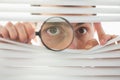 Male eyes spying through roller blind with loupe Royalty Free Stock Photo