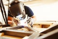 Male in face mask welds with argon-arc welding