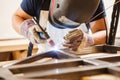 Male in face mask welds with argon-arc welding