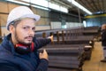 male factory worker pointing to stacks metal