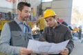 Male factory worker and supervisor analyzing plans