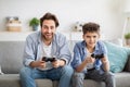 Male family leisure. Happy father and his son playing online video games and competing, using joysticks Royalty Free Stock Photo