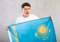 Male fan in casual clothes holds canvas of national Kazakh flag in hands and chants popular slogan