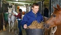 Male farm worker feeding horse Royalty Free Stock Photo