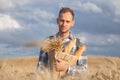 Male farmer or baker with baguettes in rye, wheat field