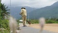 A male farmer brooming dried rice on the road in the countryside in Asia.