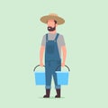 Male farmer holding water buckets gardener watering plants working in garden agricultural gardening eco farming concept