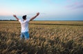 Male farmer standing in a wheat field during sunset. Man Enjoys Nature Royalty Free Stock Photo