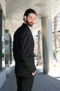 Male fashion model in black business suit standing outdoors